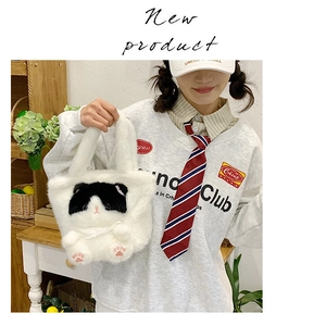 Close-up of soft white plush handbag with cute black and white cat face embroidery