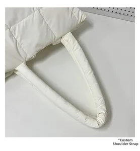 Detail of the wide padded shoulder strap on a white quilted nylon puffer tote bag