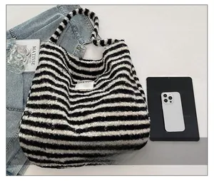 Close-up of black and white striped fuzzy tote bag with soft fleece texture and BEEYOU label