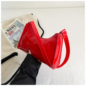 Détail du sac sous le bras en cuir verni rouge vif avec finition brillante et style baguette