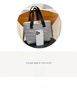 Size comparison of a black and white striped tote bag next to a smartphone