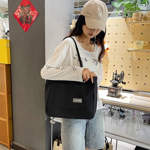 Detail of a large black nylon tote bag with fashion label shown in a lifestyle setting