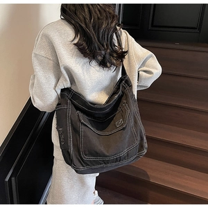 Vue latérale d'un grand sac fourre-tout en denim noir avec coutures blanches contrastées