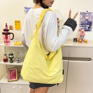 Close-up of bright yellow nylon tote bag with unique pleated texture and drawstring bow detail