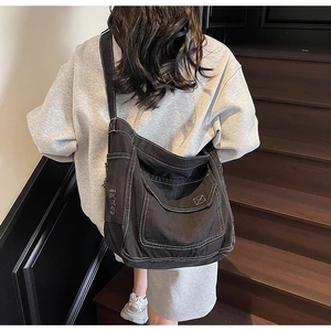 Détail du sac fourre-tout en denim noir avec surpiqûres blanches et poche effilochée