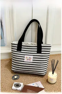 Detail view of black and white striped tote bag with colorful logo patch and web handles