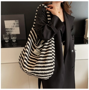 Detail of checkered fuzzy tote bag with SEEYOU label worn with a black coat