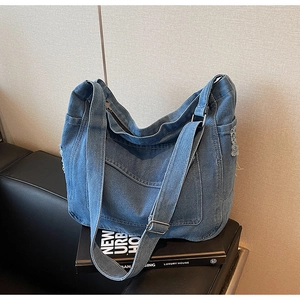 Détail du sac hobo en denim bleu avec coutures contrastées et bords effilochés vintage