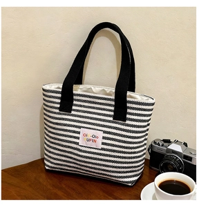 Close-up of a striped canvas tote bag on a wooden table with a vintage camera and coffee