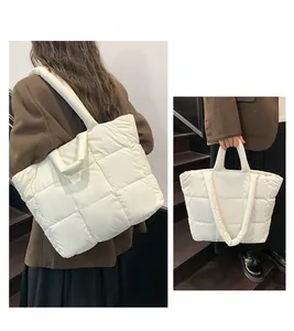 Detail of white quilted puffy tote bag showing soft square texture and wide handle