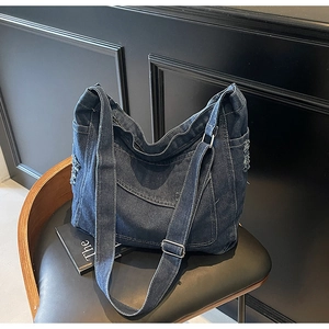 Détail du sac cabas en jean bleu avec poche effilochée et bandoulière réglable