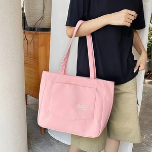 Pink nylon tote bag detail featuring a front flap pocket with a FASHION woven label