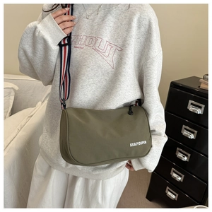 Dettaglio della borsa a tracolla in nylon verde militare con ampia tracolla a righe tricolore