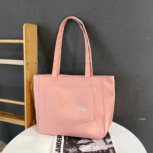 Detailed close-up of pink nylon tote bag with fashion label and front pocket design