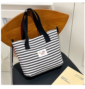 Detail of a large striped canvas tote bag on a chair, showcasing its texture and woven straps