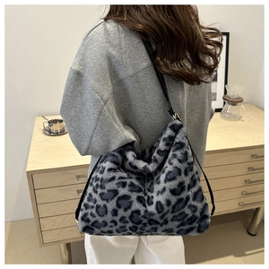 Close-up of leopard print faux fur tote bag with black leather shoulder strap on a model
