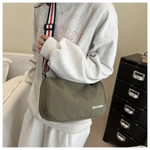 Dettaglio della borsa a tracolla in nylon verde militare con ampia tracolla rosso bianco blu