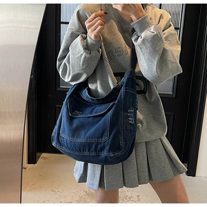 Selfie miroir montrant le grand sac bandoulière en jean bleu porté par un mannequin