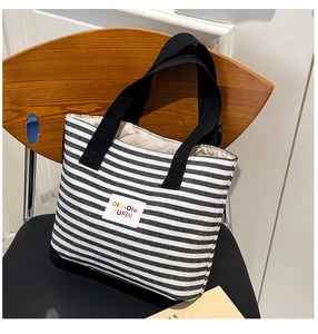 Close-up of black and white striped canvas tote bag with woven handles and brand label
