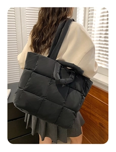 Detail of classic black quilted puffer tote bag with large square stitching and soft texture