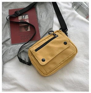 Close-up of yellow canvas crossbody bag featuring front zipper pocket and adjustable strap
