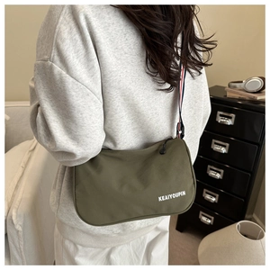 Dettaglio della borsa a tracolla in nylon verde militare con cinturino a righe