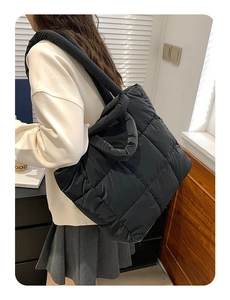 Close-up of black quilted puffer tote bag with spacious design and comfortable shoulder strap