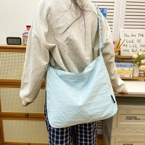 Detail of light blue nylon crossbody bag with adjustable drawstring strap and pleated texture