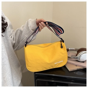 Dettaglio di una borsa a mezzaluna giallo acceso in tela con tracolla a righe tricolore