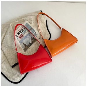 Détail de sacs baguette en cuir verni brillant rouge et orange dans un décor élégant