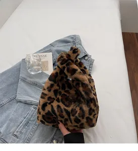 Detail of soft leopard print faux fur handbag held in a winter fashion setting