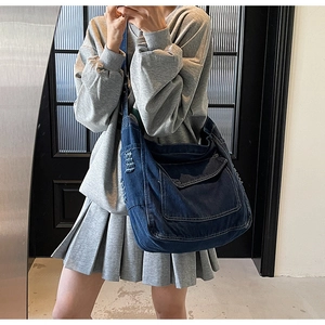 Selfie miroir montrant le grand sac bandoulière en denim bleu foncé avec surpiqûres