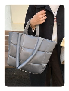 Detail of silver grey quilted tote bag with metallic puffer texture and padded handles