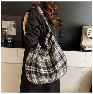 Close-up of the plush black and white plaid texture and logo label on the shoulder bag