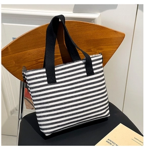 Detailed texture of black and white striped canvas tote bag on a minimalist wooden chair
