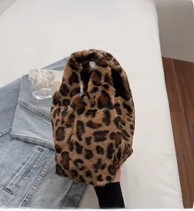 Detailed view of plush leopard print faux fur handbag held against a casual background