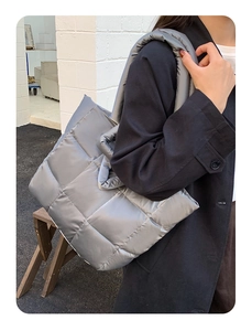 Detailed close-up of quilted puffy tote bag texture and wide padded shoulder straps