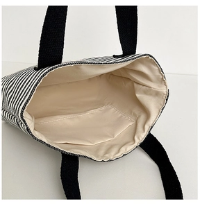 Detail view of large striped canvas tote bag showing cream lining and inner pocket