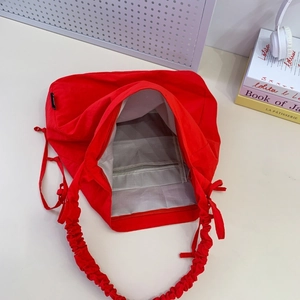 Detail view of red nylon tote bag with pleated shoulder strap and internal zipper pocket