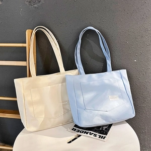 Close-up of large nylon tote bag featuring a decorative pocket and Fashion label detail