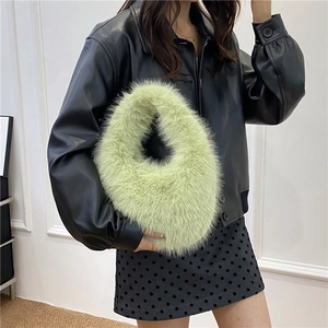 Sac à main tendance en fausse fourrure vert clair porté avec une veste en cuir noir