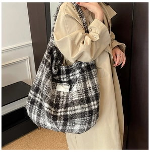 Close-up of fluffy black and white plaid tote bag with SEEYOU label on beige coat