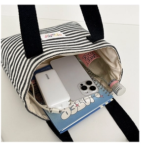 Top-down view of a striped canvas tote bag showing spacious interior with personal items