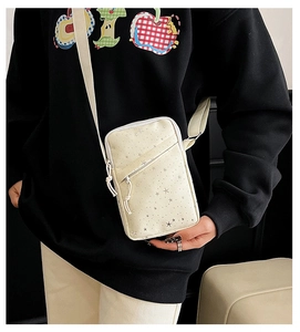 Detail of white canvas crossbody phone bag with star print and adjustable nylon strap