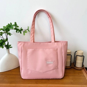 Close-up of pink nylon tote bag with fashion label on a wooden desk with green plants