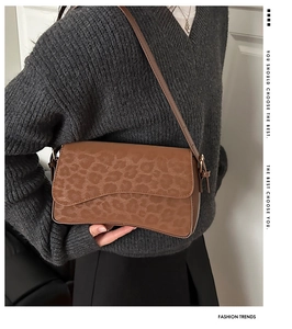 Détail d'un sac bandoulière marron motif léopard avec rabat ondulé et boucles dorées