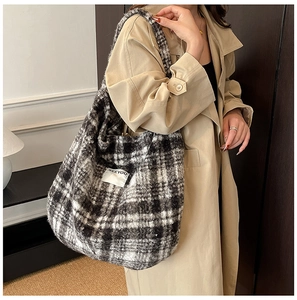 Detail of checkered plush tote bag with SEEYOU label worn with a beige trench coat