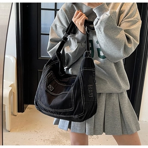 Détail du sac en denim noir avec coutures contrastées blanches et bords effilochés