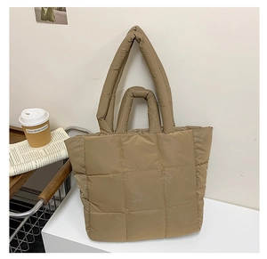 Close-up of khaki quilted puffy tote bag on a wooden tray with cozy lifestyle props