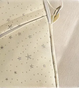 Detail view of cream shoulder bag with silver star patterns and durable twill texture
